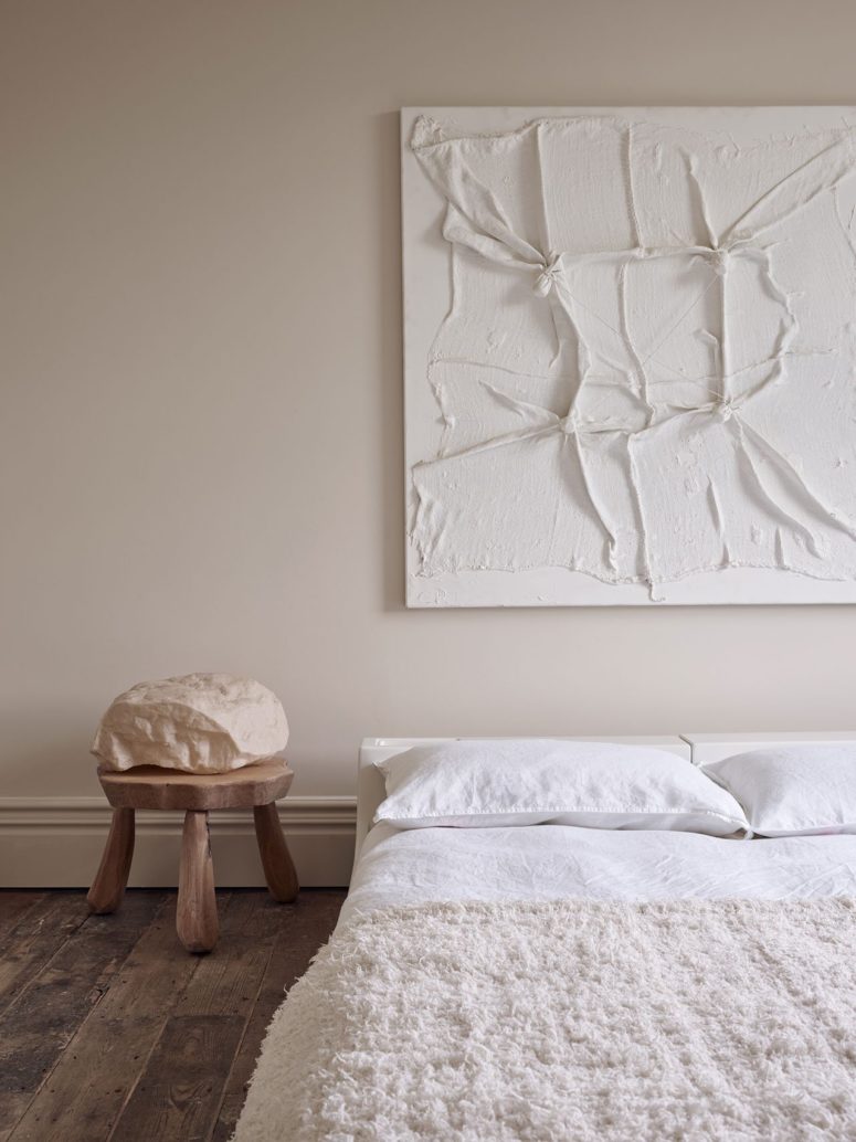 Another bedroom shows off a textural artwork and a comfy bed