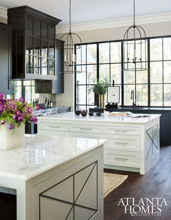 a vintage kitchen with two neutral kitchen islands with white stone countertops and lots of storage units inside