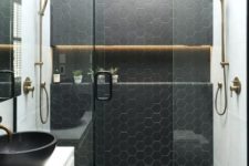 19 a black and white bathroom with hexagon tiles in the shower space and brass touches for more elegance