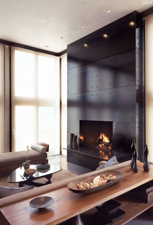 a fireplace accentuated with black metal panels looks chic and a bit industrial