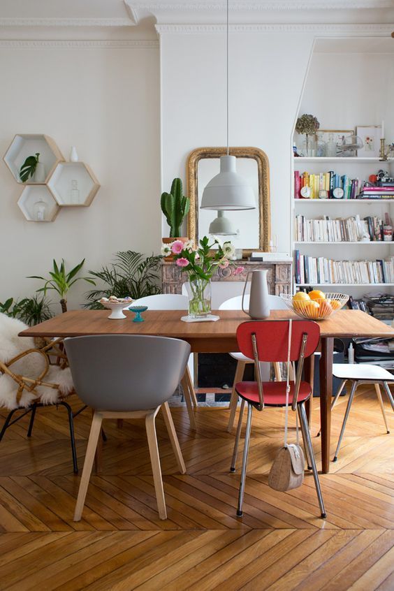 a wooden dining table with mismatching chairs in various colors and of various styles