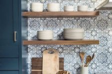 21 light-colored wooden open shelves stand out in  the blue mosai tiles and add a warm touch to the space