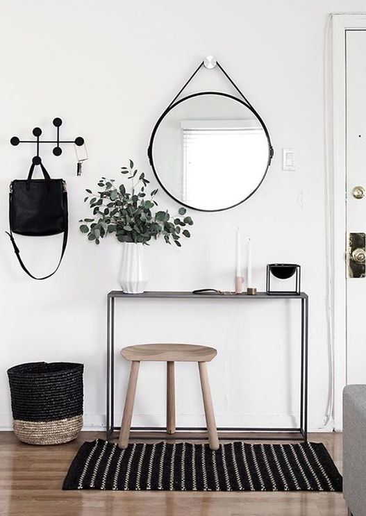a cool black and white Nordic entryway with a striped rug and some greenery in a vase