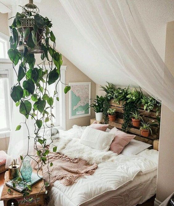 a crate shelf with potted plants and greenery and a cage with vines over the bed for a boho feel