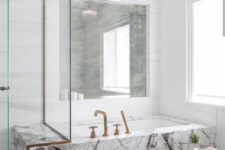 25 a neutral bathroom with a unique marble clad bathtub and brass fixtures for a more chic look