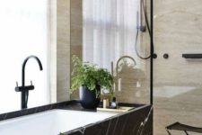 26 a black marble clad bathtub stands out a lot in a neutral warm-colored space