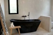 31  a minimalist meets boho bathroom with a black stone bathtub and some touches of jute and wood