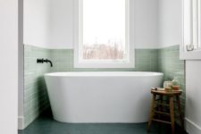 34 a contemporary bathroom with a bathtub niche covered with green tiles that match dark green floors