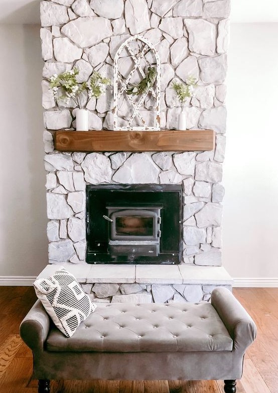a beautiful whitewashed stone fireplace with a wooden mantel with greenery looks very chic and romantic