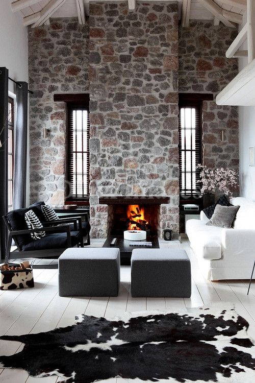 a contemporary monochromatic space with bright stone walls and a fireplace, elegant and laconic black and white furniture