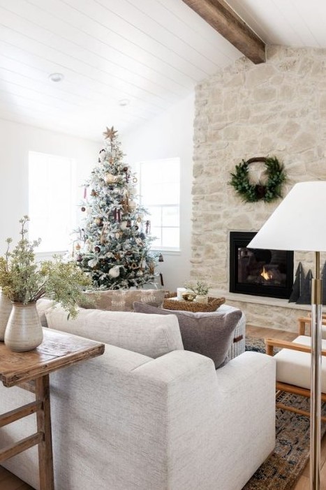 a gorgeous whitewashed stone fireplace with a wreath over it takes over the whole space and looks chic