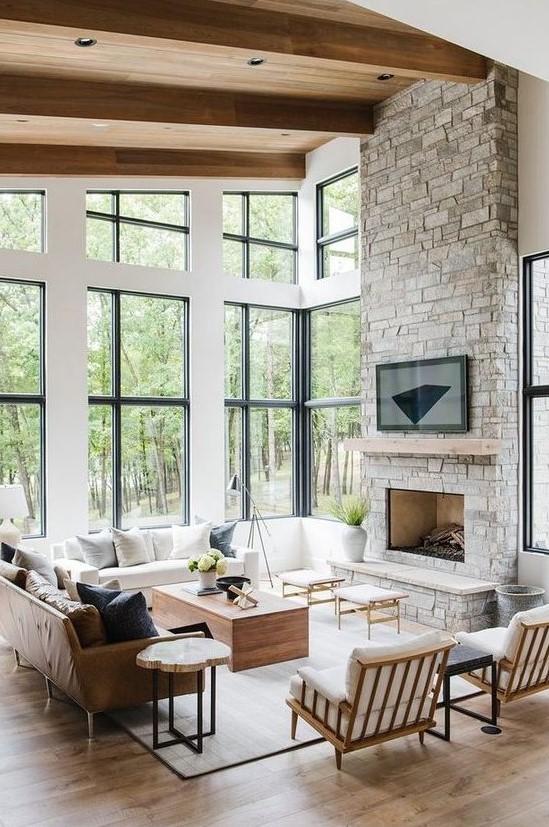 a modern rustic living room with a stone clad fireplace, wooden furniture and a leather sofa plus comfy wooden chairs