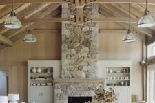 a neutral contemporary living room spruced up with a neutral stone fireplace and wooden beams