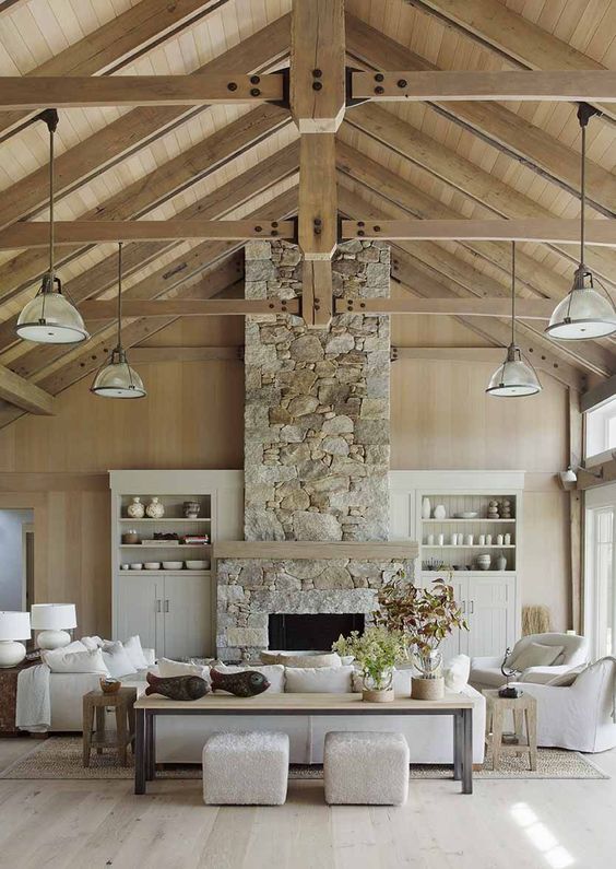 a neutral contemporary living room spruced up with a neutral stone fireplace and wooden beams