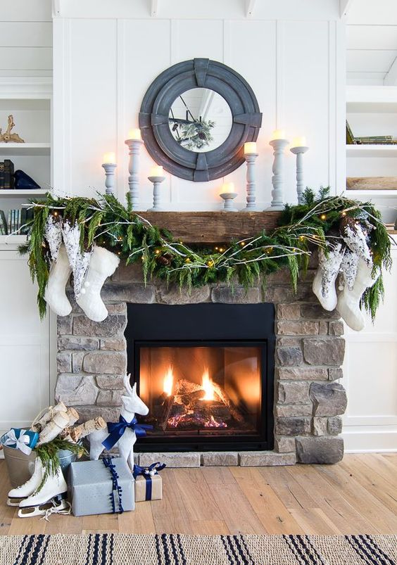 a stylish fireplace clad with stone decorated with evergreens, stockings and some candles is amazing for a farmhouse space