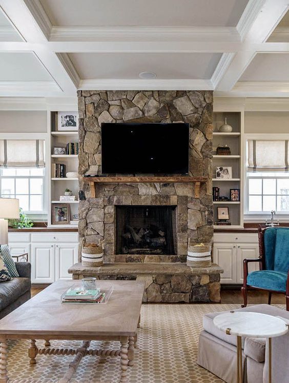 a vintage living room with a stone fireplace, a brown leather sofa, a low coffee table, built-in cabinets