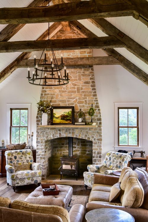 a vintage living room with a stone fireplace, printed chairs, a leather sofa and an ottoman, a tiered chandelier