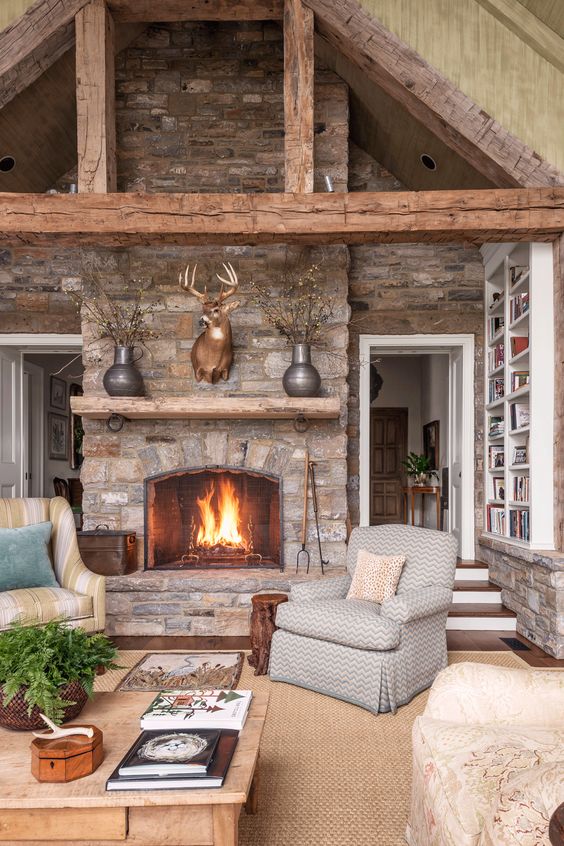 a welcoming cabin living room with stone walls and a fireplace, wooden beams, a jute rug and vintage furniture
