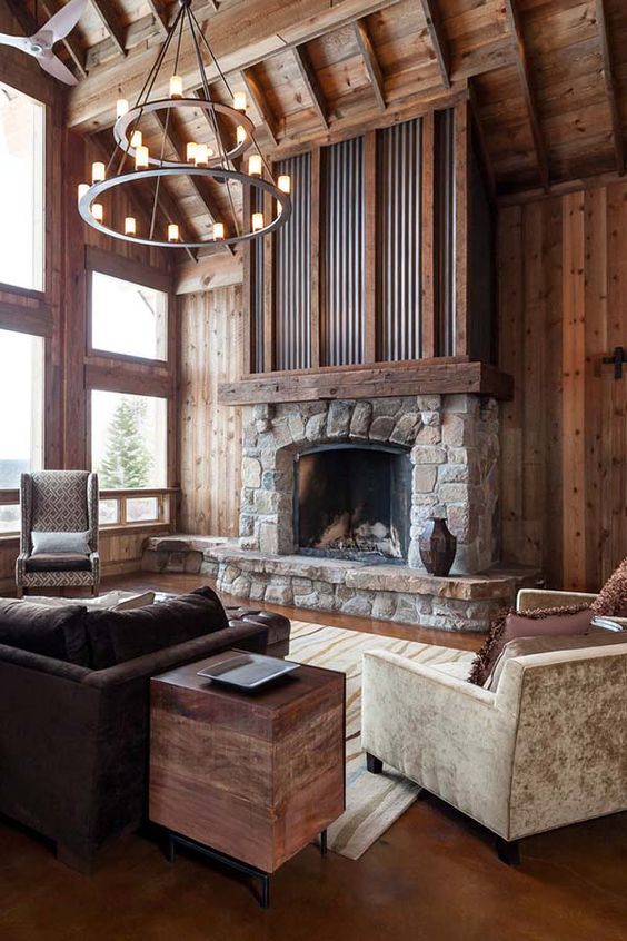 an elegant and chic cabin living room with rich stained woods, a stone and metal fireplace and vintage furniture