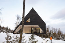 01 This dramatic A-frame cabin is located in the woods on a steep slope and is clad with dark wood