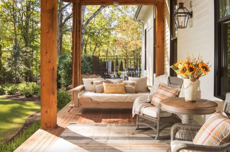 The front porch is very cozy, with wooden and wicker furniture and cozy textiles