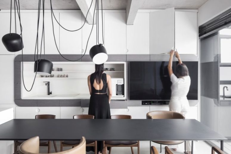 The kitchen itself is done with sleek white cabinets, with matte lamps and faucets plus a black table