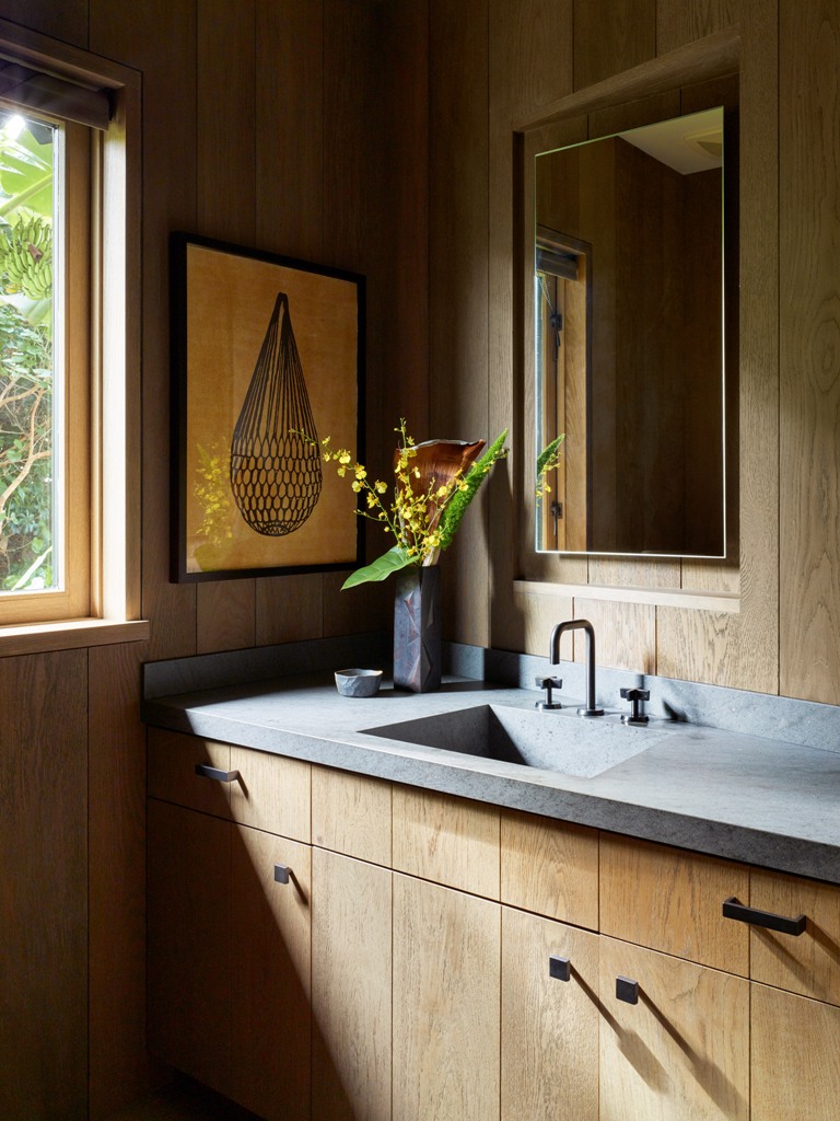 The bathroom is done with sleek plywood cabinets, a stone countertop and everything is clad with wood The bathroom is done with sleek plywood cabinets, a stone countertop and everything is clad with wood