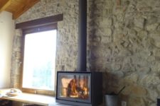 05 a modern rustic space with stone walls and a wooden ceiling plus a super modern and sleek wood burning stove