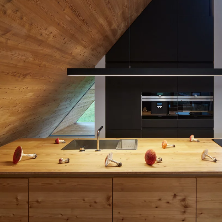 a cozy kitchen with black cabinets The kitchen features black cabinets, a wooden kitchen island and a simple long lamp to illuminate the space