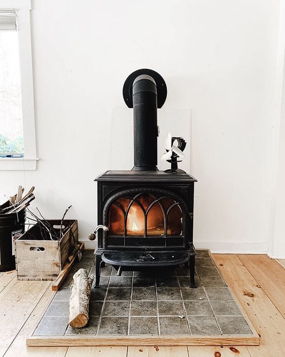 a large vintage black stove on a tile platform is a cool idea to add coziness to your home decor