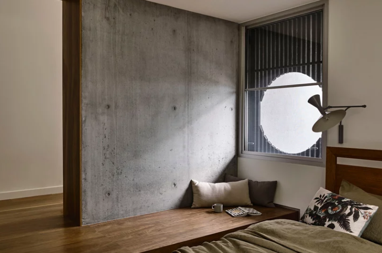 The bedroom features a bed and a platform that shapes a wooden daybed, a window made round with a bamboo screen The bedroom features a bed and a platform that shapes a wooden daybed, a window made round with a bamboo screen