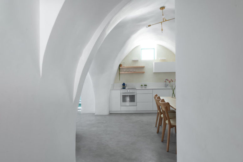 The kitchen is small and shows off some sleek white cabinets and a small window