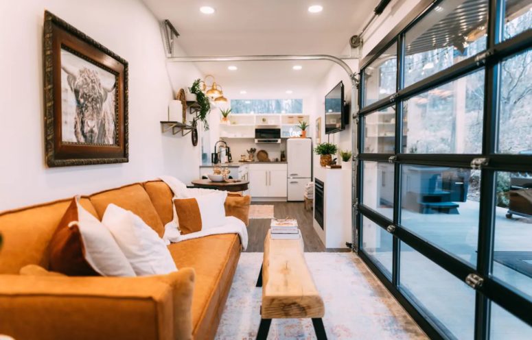 The living area features a leather sofa and a gorgeous view to enjoy through a glass door