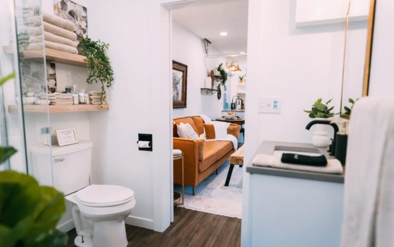The bathroom is small yet functional, there's open shelving, a shower space and a sink
