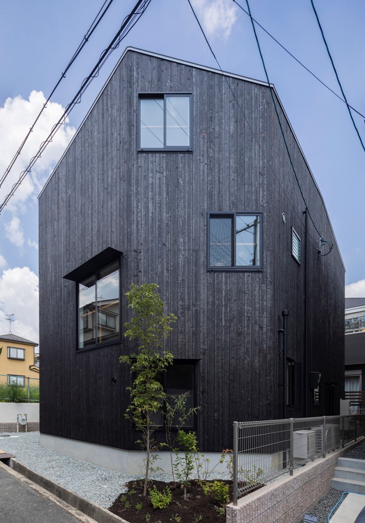 The exterior of the house is clad with blackened wood, and you can see how irregular windows are positioned
