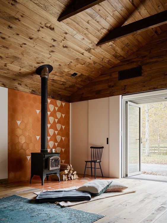 a chic mid-century modern space with a printed wall, layered rugs and pillows and a cozy vintage stove