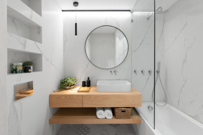 The bathroom is done with white marble and matching tiles plus elegant lamps