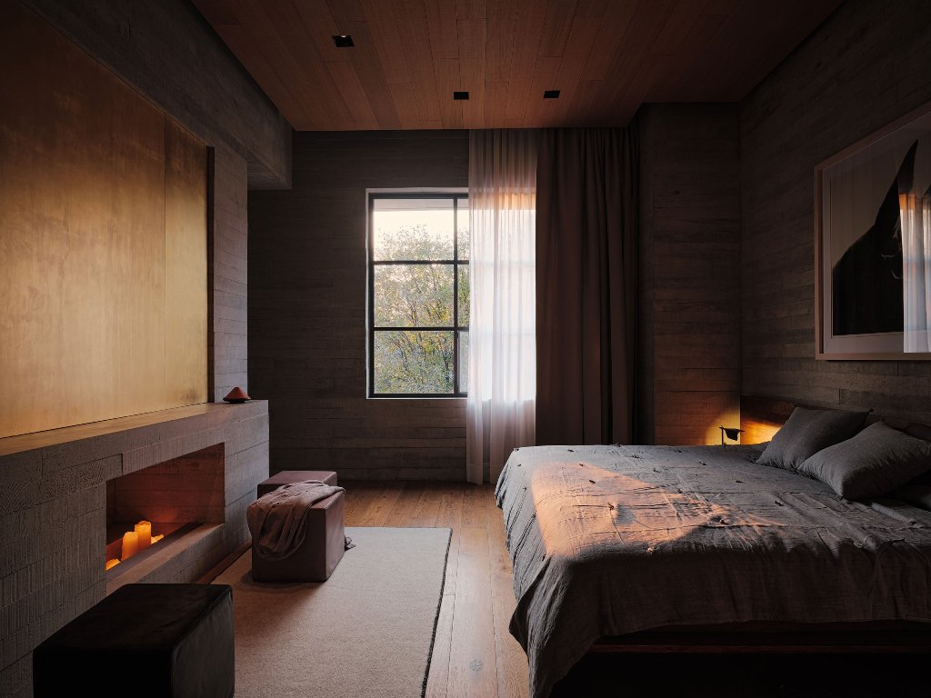 This bedroom features lots of wood, a large bed and a window, a non working fireplace with candles