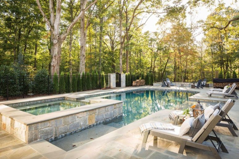 This is a pool zone, the pool is clad with stone and there are wooden chairs