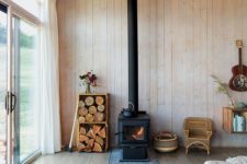 14 a cabin space fully clad with wood, with a wood burning stove and some firewood in crates for a cozy feel