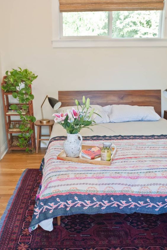 a bright bedroom with colorful bedding and a bold printed rug that give interest to the room