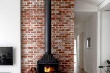 23 a wood burning stove placed in front of a brick wall to make it more safe and highlight it as much as possible