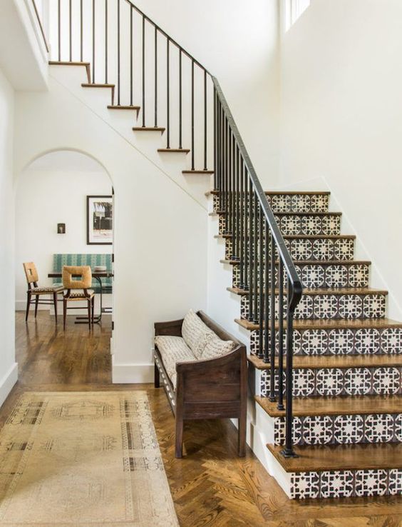 a Spanish-inspired space with printed tiles on stairs, wooden furniture and floors and wrought railing