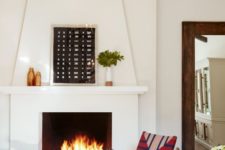 a Spanish living room with white walls and a large fireplace, printed textiles in bold colors and warm-colored artworks