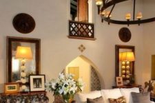 a Spanish-styled room with white walls, arched doorways, neutral furniture, vintage lamps and chandeliers