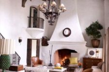 a chic yet small Spanish living room with white plaster walls, a large fireplace, some colored accents and leather chairs