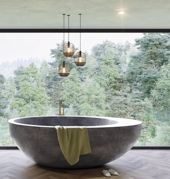 a contemporary bathroom with a glazed wall for a view, a rounded stone bathtub, catchy lamps to accent the space