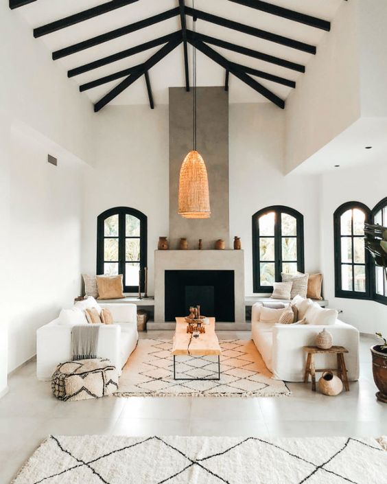 a contemporary meets traditional Spanish living room with a concrete fireplace, neutral furniture and printed textiles