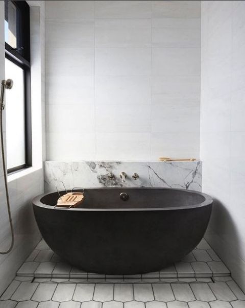 a contemporary monochromatic bathroom with a blakc stone wall, marble and geometric tiles and dark fixtures for a bold look
