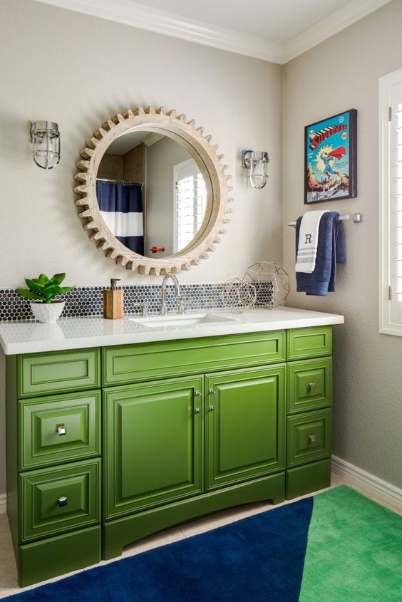 a kids' bathroom with a green vanity, a color block rug, a wooden frame mirror and character posters
